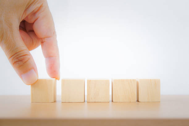 istock hand holding blank wooden cube, with blurred others on wood desk, for infographic icon, input wording and  create icon symbol to success concept 1355420030