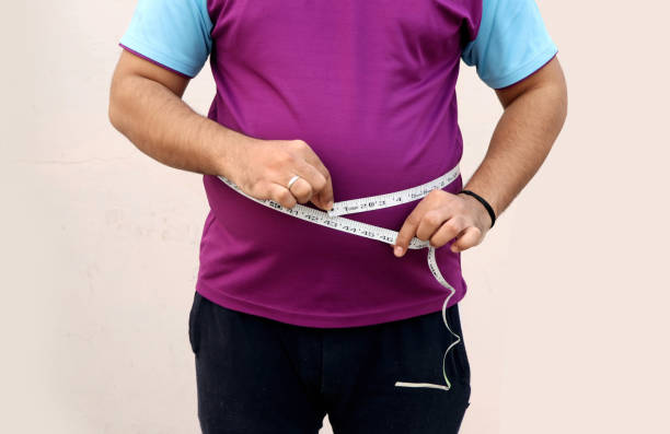 istock A asian men measures his fat belly with a measuring tape on a plain background 1355420784