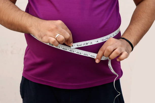 istock A asian men measures his fat belly with a measuring tape on a plain background 1355420786