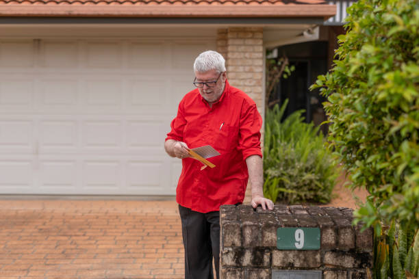 istock Senior Man Checks his Letterbox for Mail 1355420863