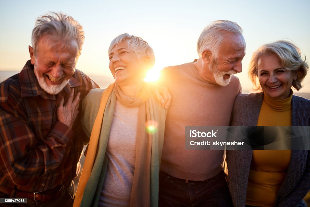 Happy mature couples talking while walking in autumn day. Happy senior couples communicating while walking in autumn at sunset. Senior Adult Stock Photo