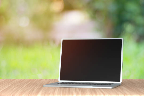 istock Laptop on the table in front of green nature background. 1355427165