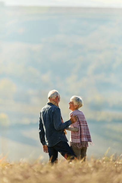 istock Happy senior couple talking while enjoying on a hill in autumn day. 1355428122