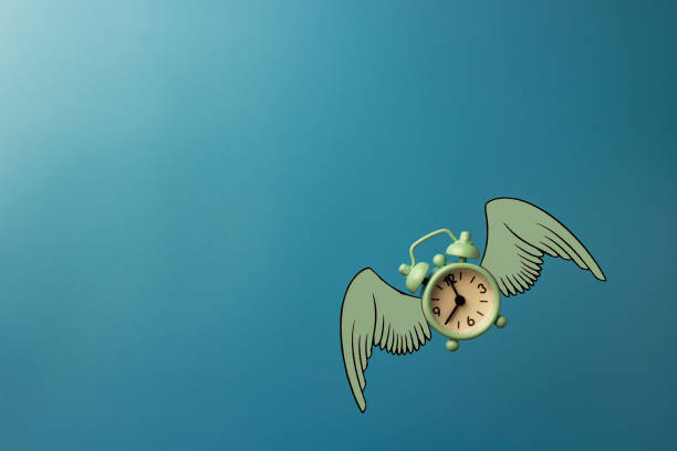 istock Flying alarm clock with wings on blue background. 1355429229