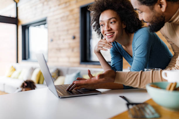 istock Happy African American couple using laptop in dining room. 1355429952