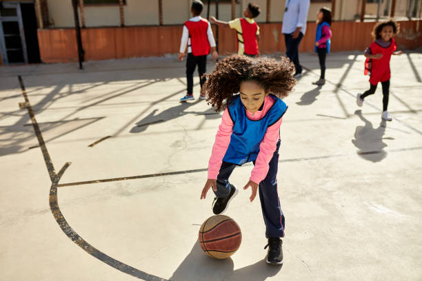 aktywna wielorasowa uczennica grająca w koszykówkę na świeżym powietrzu - basketball playing ball african descent zdjęcia i obrazy z banku zdjęć