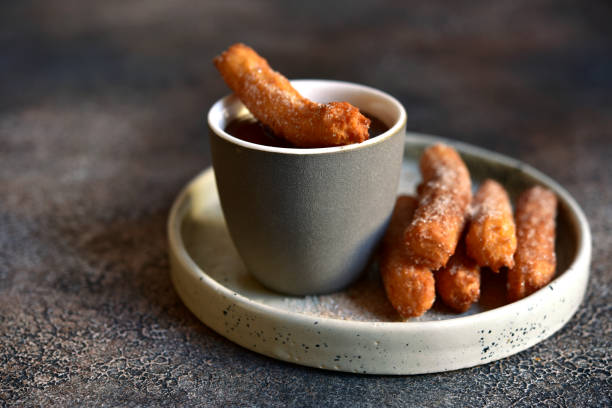 istock Traditional spanish dessert churros - fried choux pastry with chocolate sauce 1355431080