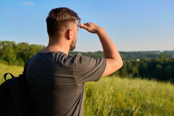 istock Middle-aged bearded man with a backpack on a hike looking at the horizon 1355432077