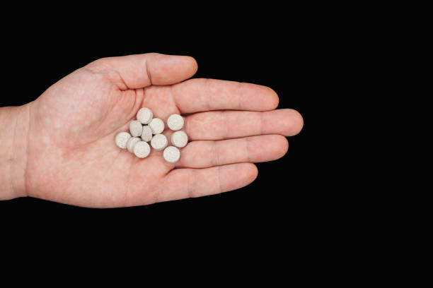 istock Male hand holding pills. Capsules are white. Medicines. Isolate 1355433228