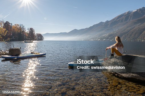istock Young woman docking a stand up paddle on a rock 1355433299