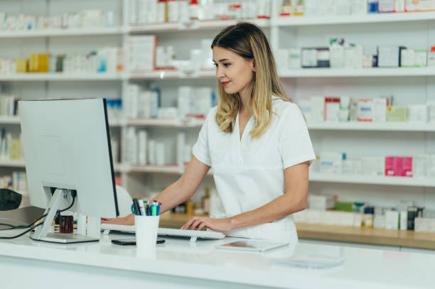 portrait of a beautiful female pharmacist working in a pharmacy - note pad medicine healthcare and medicine pharmacy imagens e fotografias de stock