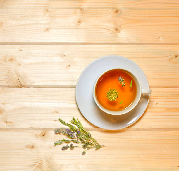 istock A cup with floral broth and dried grass on a light wooden countertop. 1355436480