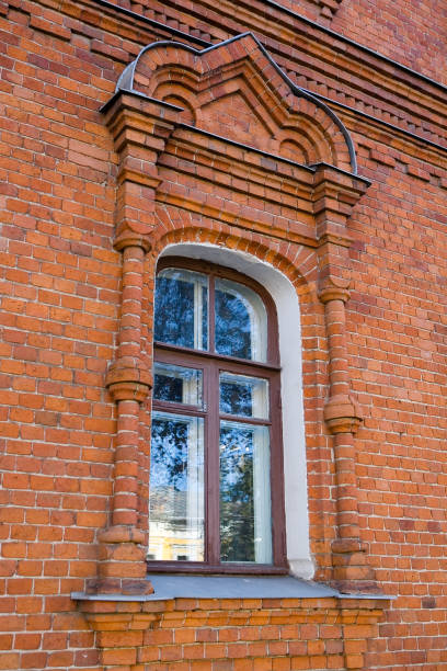 Old red brick wall with a a window on an autumn day.
