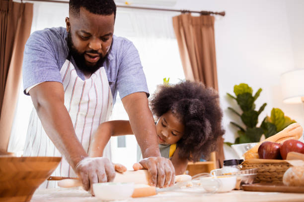 istock Happy African American father and daughter having fun while preparing cookie dough at home. happy family time. 1355440020