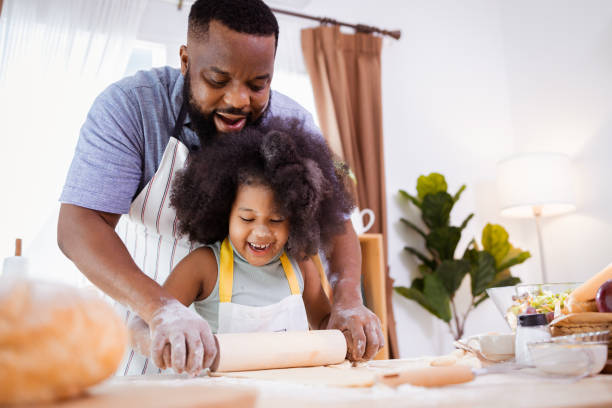istock Happy African American father and daughter having fun while preparing cookie dough at home. happy family time. 1355440101