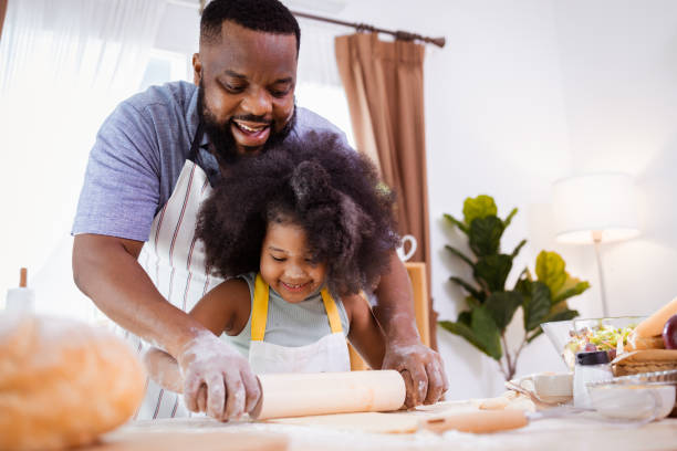 istock Happy African American father and daughter having fun while preparing cookie dough at home. happy family time. 1355440161