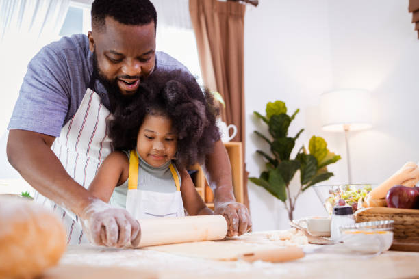 istock Happy African American father and daughter having fun while preparing cookie dough at home. happy family time. 1355440183