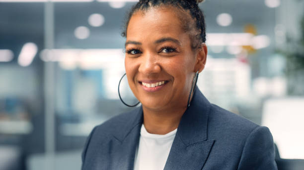 portrait d’une femme afro-américaine d’âge moyen adulte heureuse et confiante portant une veste sombre, regardant l’appareil photo, posant et souriant avec charme. femme noire prospère travaillant dans des bureaux d’entreprise diversifiés. - charmingly photos et images de collection