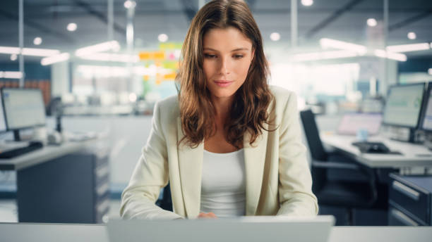 istock Young Happy Businesswoman Using Computer in Modern Office with Colleagues. Stylish Beautiful Manager Smiling, Working on Commercial, Financial and Marketing Projects. Specialist in Diverse Team. 1355440544