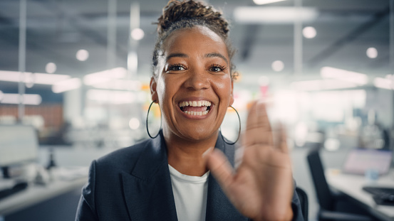 Retrato de la gerente afroamericana saludando a los clientes en videollamada en la oficina moderna. Conferencia telefónica de negocios en la computadora con socios, colegas, familiares o amigos. Vista POV. photo