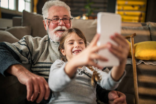 istock Happy grandad with granddaughter using mobil phone 1355446540