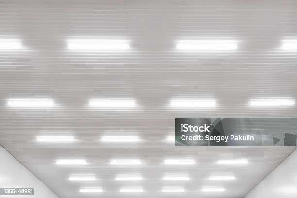 Many Led Industrial Lamps Hang On White Ceiling In Production Hall Or Hangar And Shine Bright Light Background Stock Photo - Download Image Now