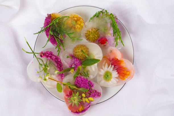 istock Various flowers in ice cubes. Creative floral background. Frozen beautiful plants. 1355449347