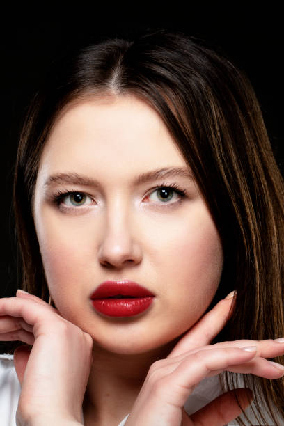 istock Beautiful girl model with red sensual lips on a black background. 1355450187