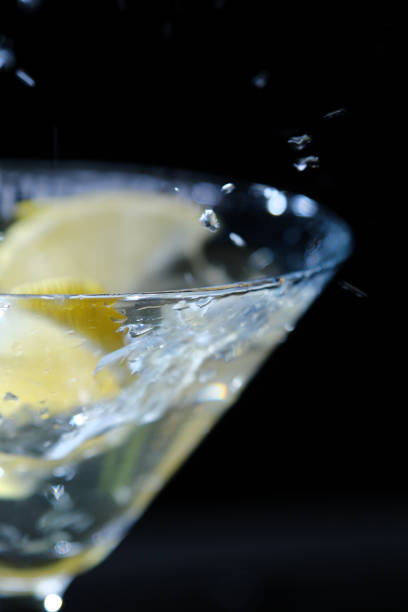 istock Slice of lemon is falling into martini glass 1355453931