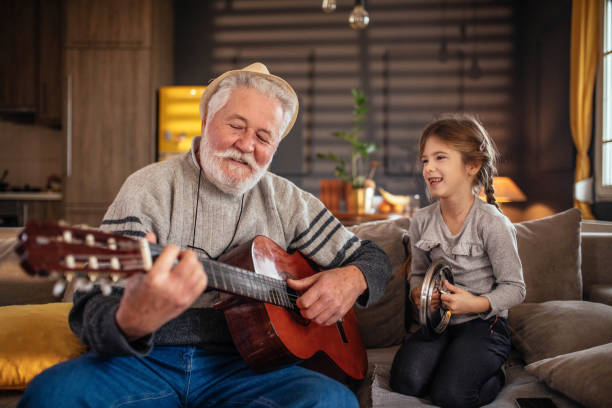 little girl having fun with her grandfather at home stock photo