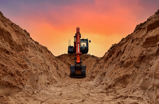 Excavadora excava zanja en el fondo de la puesta de sol. Backgoe en el movimiento de tierras. Construcción de gasoducto de gas natural. photo