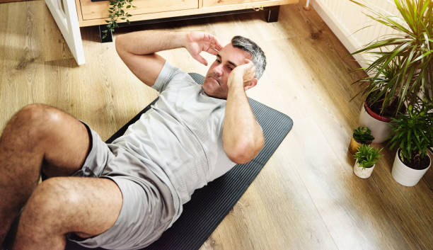 shot of a mature man doing crunches to strengthen his core at home - 仰臥起坐 個照片及圖片檔