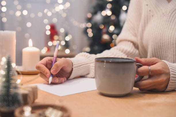 クリスマスのウィッシュリスト、目標を書くペンとカップを持つ女性の手 - wish list ストックフォトと画像