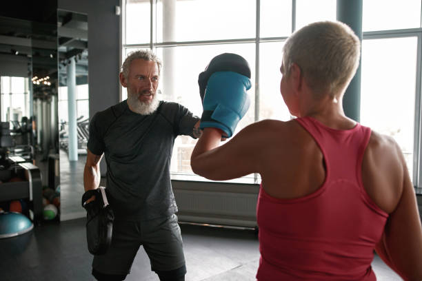 istock Woman exercising with trainer at boxing and self defense lesson 1355461886