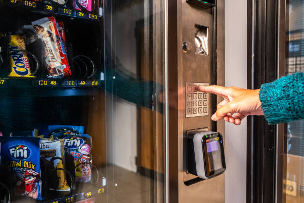 une femme utilise un distributeur automatique pour acheter de la nourriture et des boissons dans la rue à valence, en espagne - vending machine photos et images de collection
