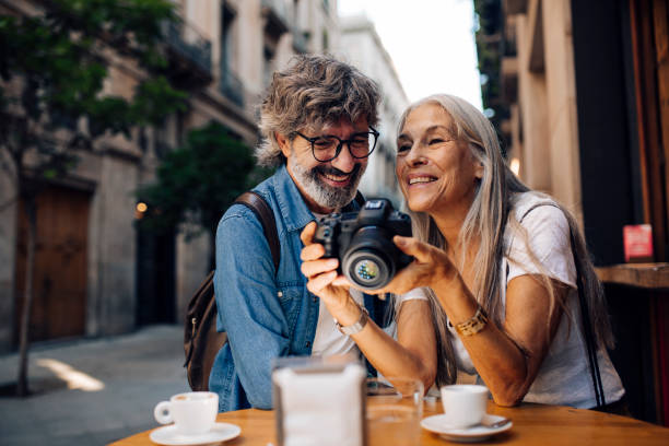 pareja madura de vacaciones disfrutando en la cafetería y viendo sus fotos - senior couple fotos fotografías e imágenes de stock