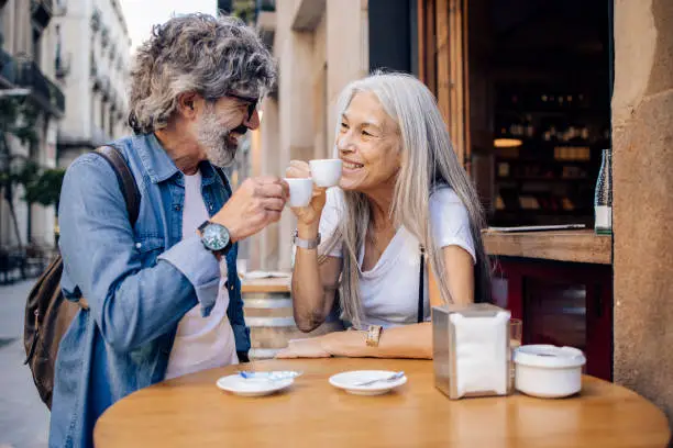 Photo of Mature couple on a journey enjoying espresso at the sidewalk cafe