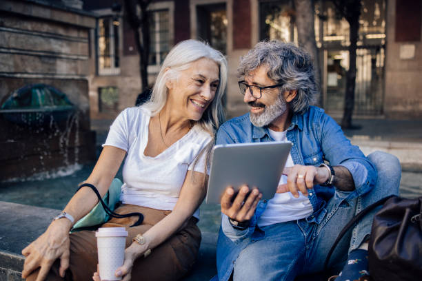 reifes paar macht eine pause beim sightseeing und mit tablet - women digital tablet outdoors smiling stock-fotos und bilder