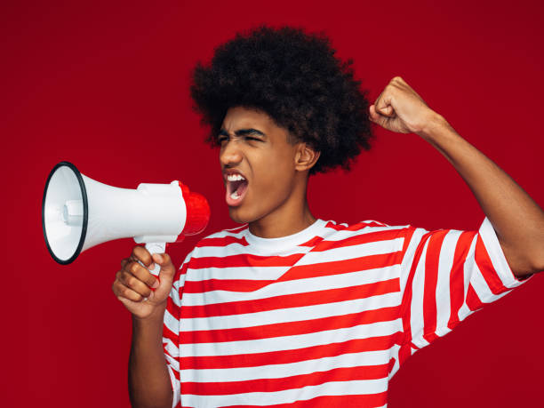 istock Portrait of afro guy holding a megaphone 1355469774