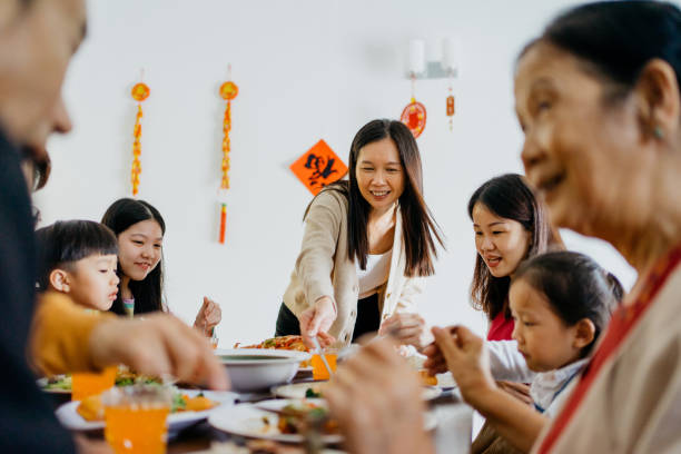 familia china asiática de varias generaciones que tiene una cena de reunión de nochevieja china en casa - típico oriental fotografías e imágenes de stock