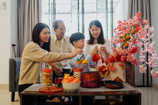 Image of an Asian Chinese family decorating living room and preparing for Chinese New Year family reunion
