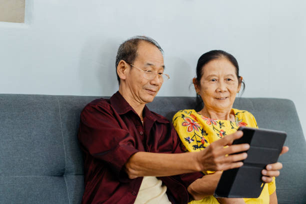 istock Asian senior couple using digital tablet in living room 1355470022