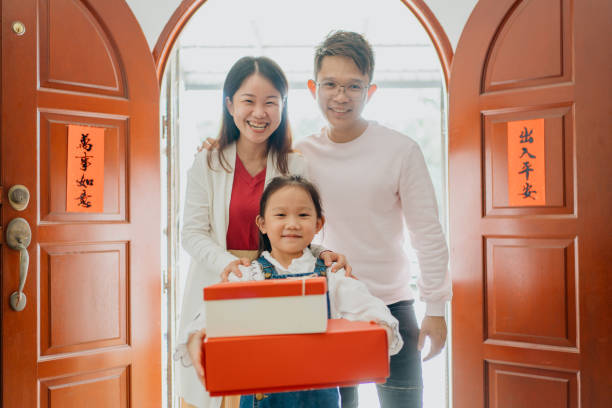 istock Smiling young girl carrying gift box while visiting relatives during Chinese New Year 1355470044