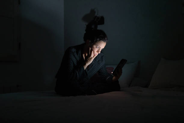 mujer usando su teléfono inteligente a altas horas de la noche. - adicción fotos fotografías e imágenes de stock
