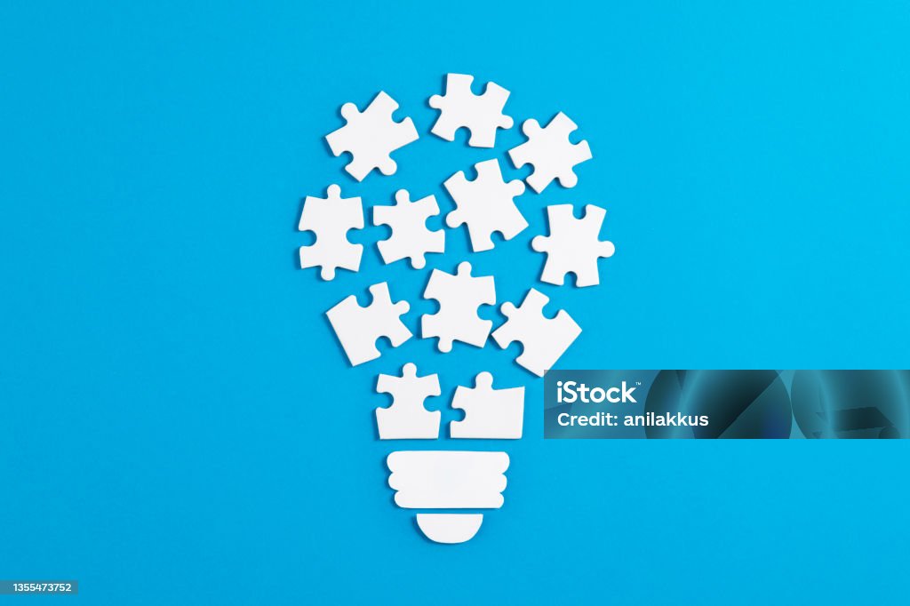 Idea Light Bulb Puzzle on Blue Background Light bulb puzzle pieces on blue background Inspiration Stock Photo