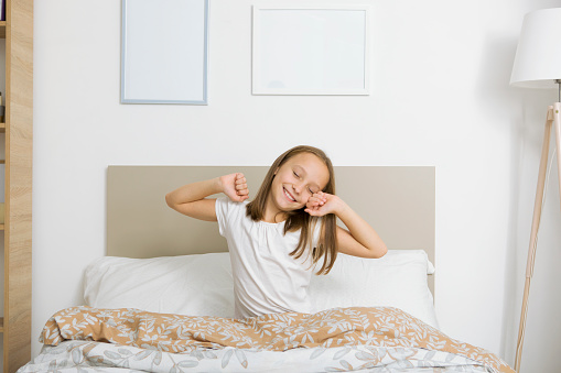 Little girl in good mood in pajamas in the bedroom. High quality photo