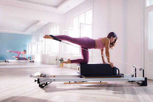 Happy athletic woman exercising on a Pilates machine.