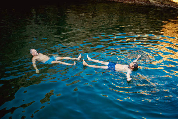 istock Middle aged gay couple floating on water facing each other 1355478361