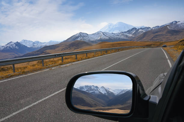 Caucasus Mountains are displayed in the rear view mirror of a car The Caucasus Mountains are displayed in the rear view mirror of a car on the way to Mount Elbrus, Russia rear view mirror stock pictures, royalty-free photos & images