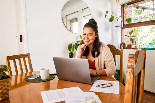 scatto di una giovane donna attraente che usa il suo laptop al tavolo mentre lavora da casa - businesswoman form finance women foto e immagini stock